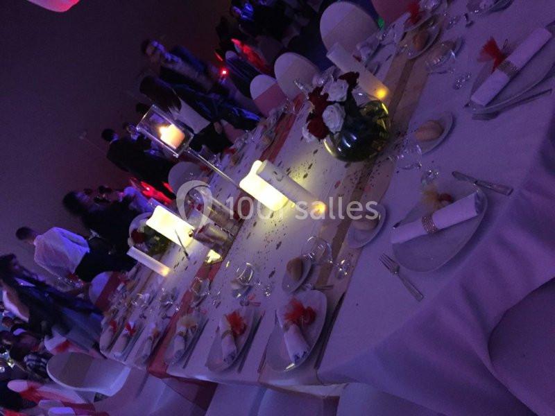 Table dressée pour un événement, décorée de bougies, fleurs et serviettes, entourée de convives dans une ambiance tamisée.