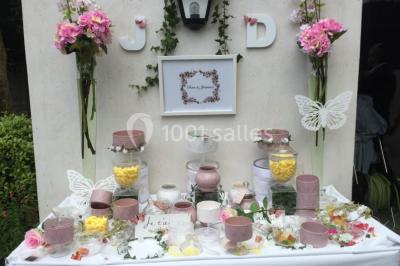 Miniature Location salle Saint-Maximin (Oise) - L'Art d'Oise #29 Salle décorée pour un événement, avec des tables rondes dressées, chaises rouges et un fond floral rose.