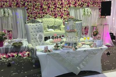 Miniature Location salle Saint-Maximin (Oise) - L'Art d'Oise #16 Salle décorée pour un événement, avec des tables rondes dressées, chaises rouges et un fond floral rose.