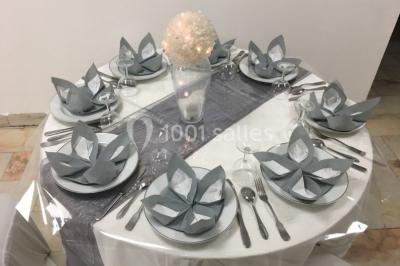 Miniature Location salle Saint-Maximin (Oise) - L'Art d'Oise #30 Salle décorée pour un événement, avec des tables rondes dressées, chaises rouges et un fond floral rose.