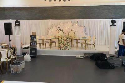 Miniature Location salle Saint-Maximin (Oise) - L'Art d'Oise #34 Salle décorée pour un événement, avec des tables rondes dressées, chaises rouges et un fond floral rose.