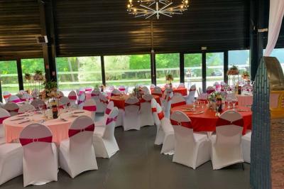 Miniature Location salle Saint-Maximin (Oise) - L'Art d'Oise #13 Salle décorée pour un événement, avec des tables rondes dressées, chaises rouges et un fond floral rose.