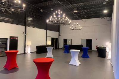 Miniature Location salle Saint-Maximin (Oise) - L'Art d'Oise #4 Salle décorée pour un événement, avec des tables rondes dressées, chaises rouges et un fond floral rose.