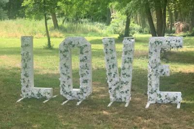 Miniature Location salle Saint-Maximin (Oise) - L'Art d'Oise #40 Salle décorée pour un événement, avec des tables rondes dressées, chaises rouges et un fond floral rose.