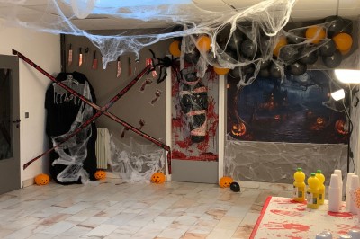Salle décorée avec des tables rondes, nappes blanches et chaises rouges, prête pour un événement festif.