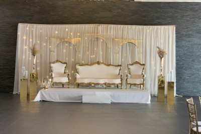 Salle décorée avec des tables rondes, nappes blanches et chaises rouges, prête pour un événement festif.