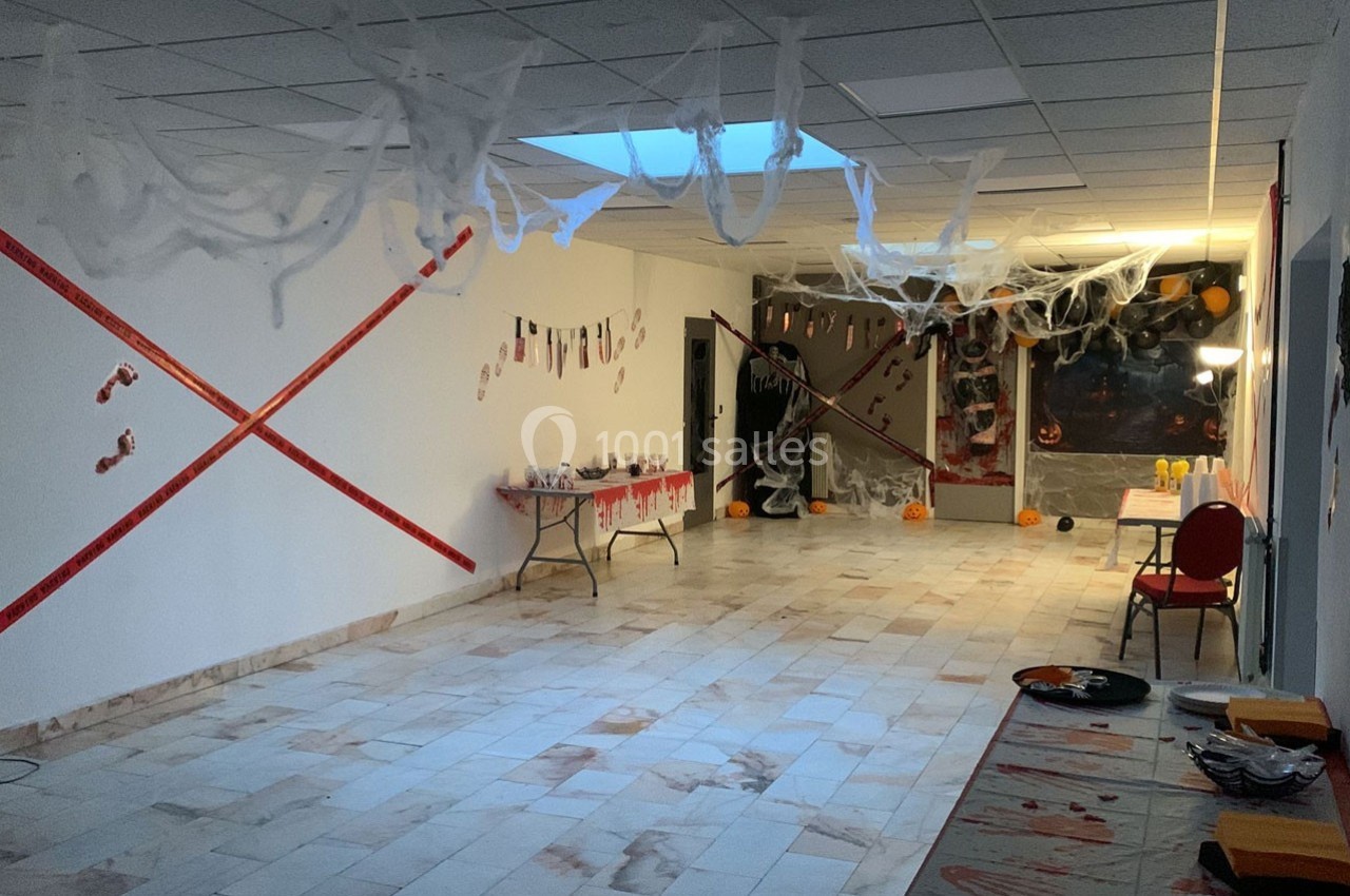 Salle décorée pour Halloween avec des toiles d’araignée, des citrouilles et des rubans rouges sur les murs.