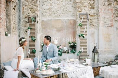 Chaises transparentes disposées en rangées sur une allée blanche, entourées d'arbres dans un cadre extérieur.