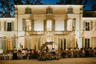 Chaises transparentes disposées en rangées sur une allée blanche, entourées d'arbres dans un cadre extérieur.