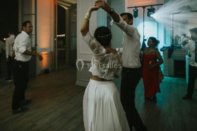 Chaises transparentes disposées en rangées sur une allée blanche, entourées d'arbres dans un cadre extérieur.