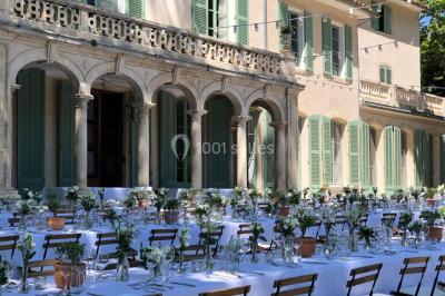 Chaises transparentes disposées en rangées sur une allée blanche, entourées d'arbres dans un cadre extérieur.