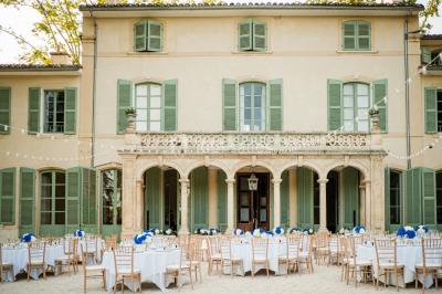 Chaises transparentes disposées en rangées sur une allée blanche, entourées d'arbres dans un cadre extérieur.