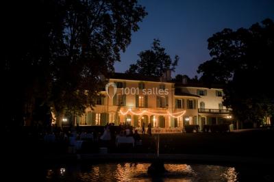 Chaises transparentes disposées en rangées sur une allée blanche, entourées d'arbres dans un cadre extérieur.