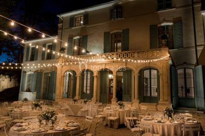 Chaises transparentes disposées en rangées sur une allée blanche, entourées d'arbres dans un cadre extérieur.