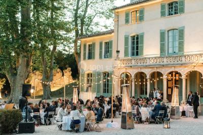 Chaises transparentes disposées en rangées sur une allée blanche, entourées d'arbres dans un cadre extérieur.