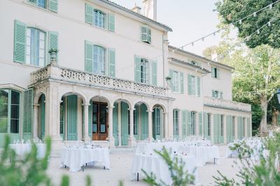 Chaises transparentes disposées en rangées sur une allée blanche, entourées d'arbres dans un cadre extérieur.