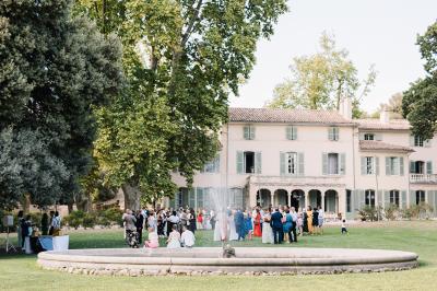 Chaises transparentes disposées en rangées sur une allée blanche, entourées d'arbres dans un cadre extérieur.