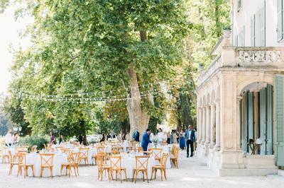 Chaises transparentes disposées en rangées sur une allée blanche, entourées d'arbres dans un cadre extérieur.