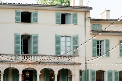 Chaises transparentes disposées en rangées sur une allée blanche, entourées d'arbres dans un cadre extérieur.