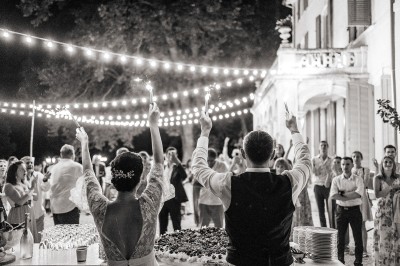 Chaises transparentes disposées en rangées sur une allée blanche, entourées d'arbres dans un cadre extérieur.