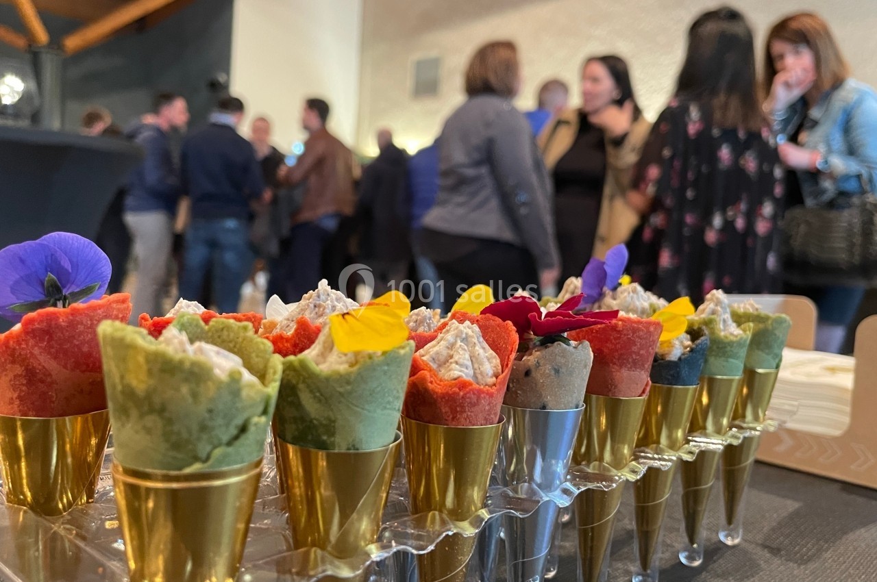 Cônes apéritifs colorés garnis de mousse, décorés de fleurs comestibles, présentés sur une table lors d'un événement.