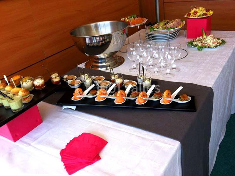 Buffet avec verrines, cuillères apéritives, salades et verres disposés sur une table drapée.