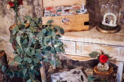 Scooter rose décoré de fleurs roses et blanches, stationné près d'un mur en pierre et d'une porte en bois.