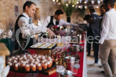 Scooter rose décoré de fleurs roses et blanches, stationné près d'un mur en pierre et d'une porte en bois.