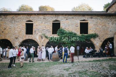 Scooter rose décoré de fleurs roses et blanches, stationné près d'un mur en pierre et d'une porte en bois.