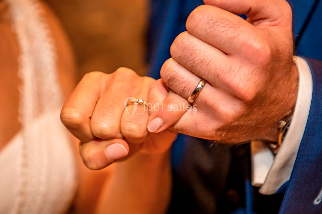 Deux mains entrelacées montrant des alliances, symbolisant une union ou un mariage.