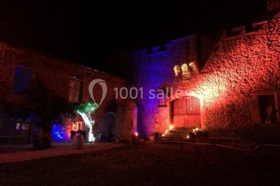 Scooter rose décoré de fleurs roses et blanches, stationné près d'un mur en pierre et d'une porte en bois.