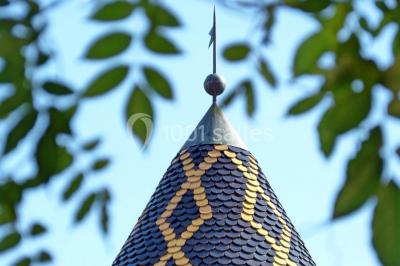 Scooter rose décoré de fleurs roses et blanches, stationné près d'un mur en pierre et d'une porte en bois.