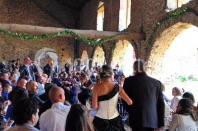 Scooter rose décoré de fleurs roses et blanches, stationné près d'un mur en pierre et d'une porte en bois.