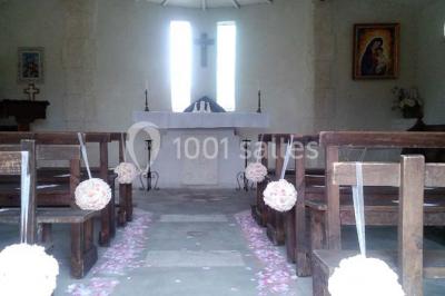Petite chapelle en pierre éclairée par des lumières colorées dans un environnement nocturne.
