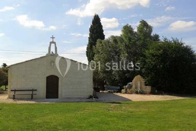 Petite chapelle en pierre éclairée par des lumières colorées dans un environnement nocturne.