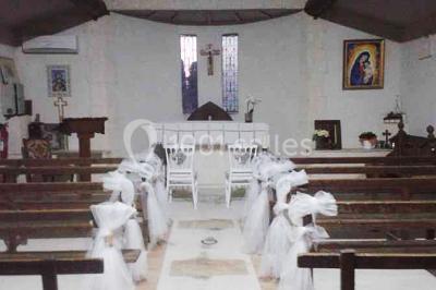 Petite chapelle en pierre éclairée par des lumières colorées dans un environnement nocturne.