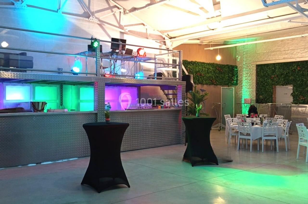 Location salle Tourcoing (Nord) - Latin Dance #18 Salle moderne avec mezzanine, éclairages colorés, tables dressées et plantes décoratives.
