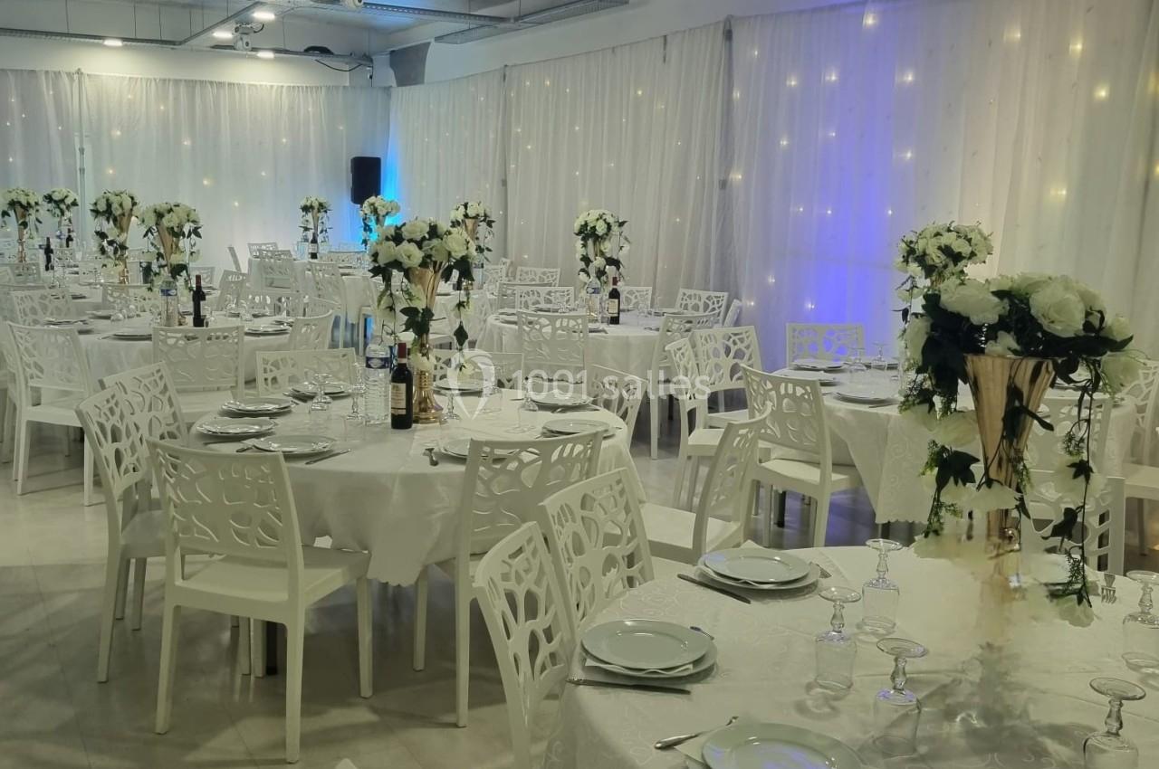 Location salle Tourcoing (Nord) - Latin Dance #4 Salle de réception décorée avec des tables rondes, nappes blanches, chaises ajourées et centres de table fleuris.