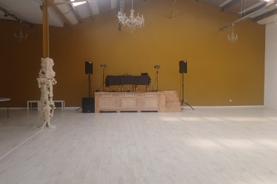 Salle de réception décorée avec des tables blanches, des colonnes fleuries et un tapis rouge menant à une estrade.