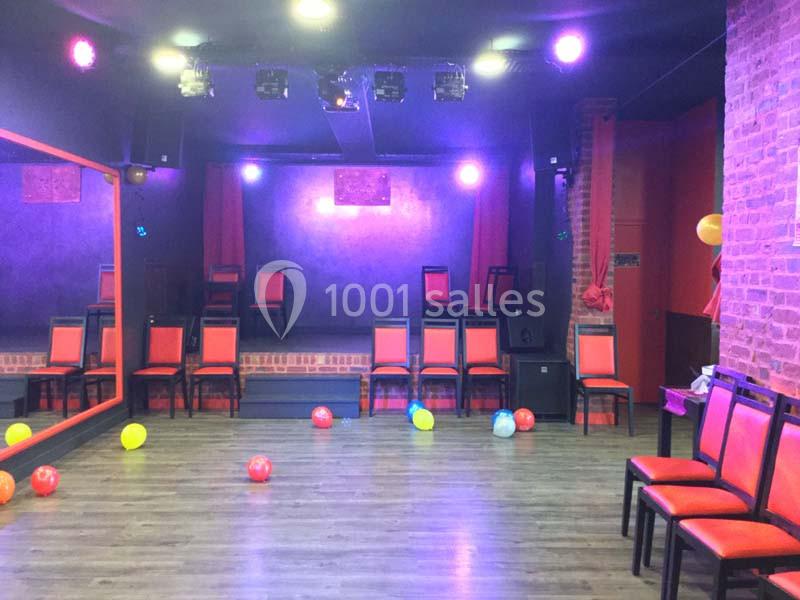 Location salle Tourcoing (Nord) - Latin Dance #11 Salle vide avec des chaises rouges alignées, un parquet, des ballons colorés au sol et une petite scène en arrière-plan.