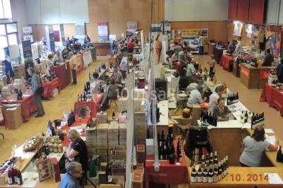 Salle de réception avec tables rondes dressées, éclairage coloré et scène équipée pour un événement.