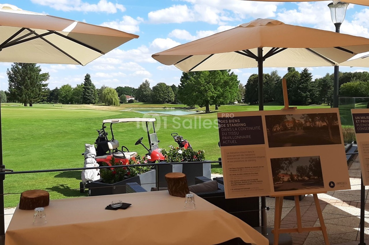 Panneaux d'information disposés sur une terrasse avec vue sur un terrain de golf sous un ciel ensoleillé.
