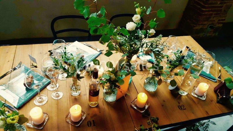 Table en bois décorée avec des bougies, des fleurs et des verres, prête pour un repas ou une réception conviviale.