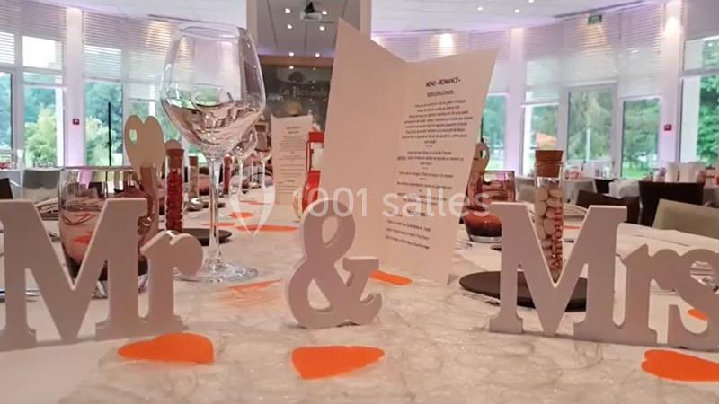 Décoration de table de mariage avec des lettres ’Mr & Mrs’, des verres à vin et un menu au centre.