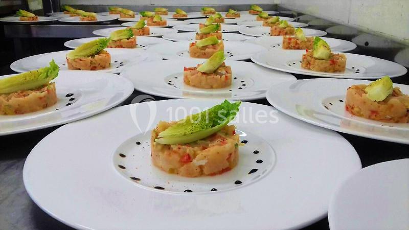 Assiettes dressées avec des tartares de poisson, garnis de salade et d'avocat, alignées sur un plan de travail.