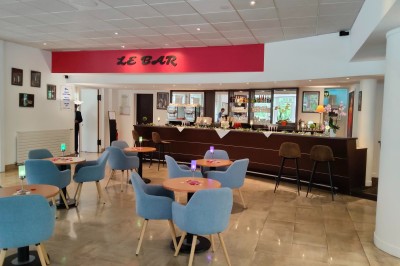 Chambre d'hôtel lumineuse avec un lit double, un bureau près d'une fenêtre et des murs partiellement violets.