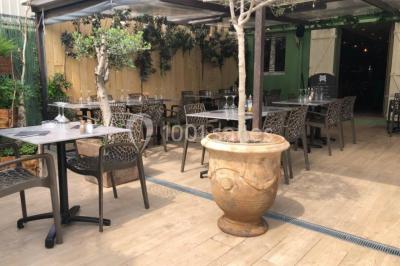 Miniature Location salle Vallauris (Alpes-Maritimes) - L'Adresse #12 Terrasse extérieure avec tables dressées, chaises en métal ajouré, plantes et pergola partiellement couverte.