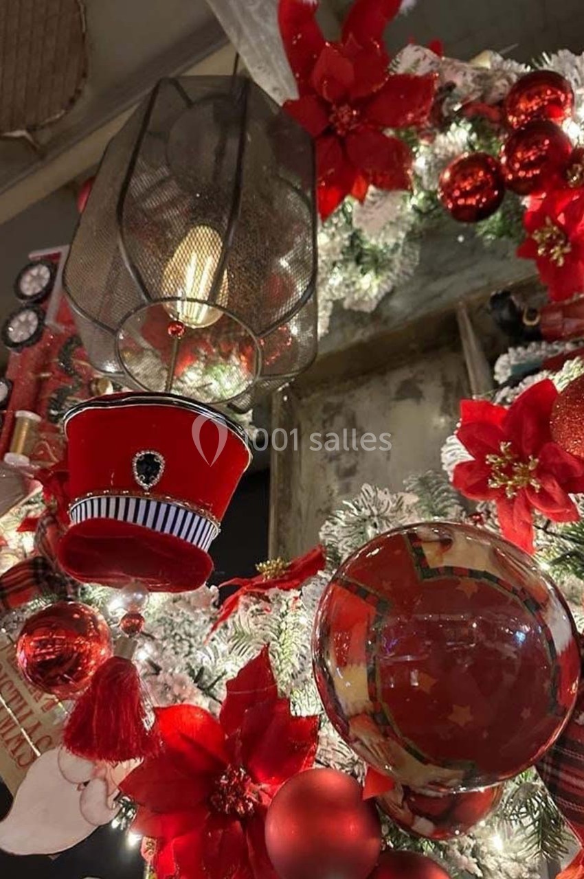 Décoration de Noël avec couronne ornée de poinsettias rouges, boules brillantes et petits accessoires festifs.