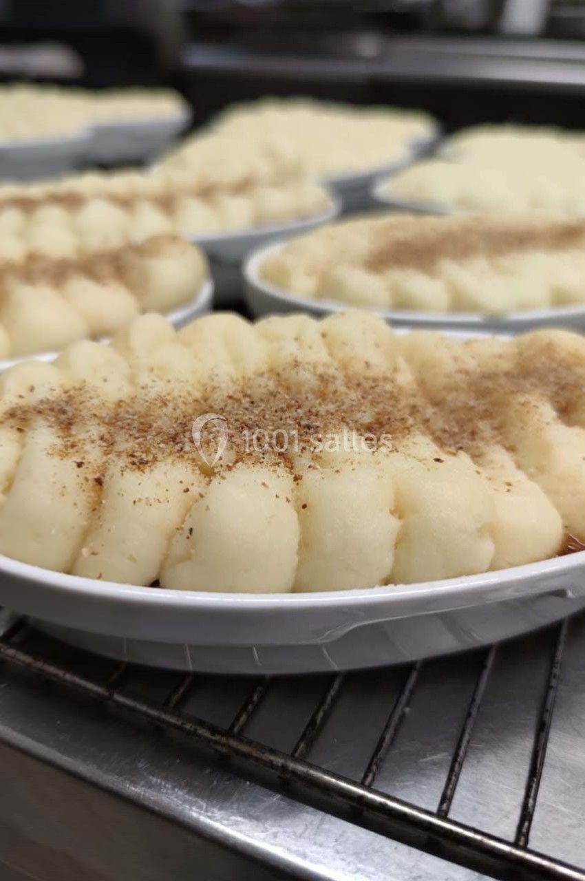 Purée de pommes de terre dressée en rosaces dans des plats individuels, saupoudrée d'épices, sur une grille en cuisine.