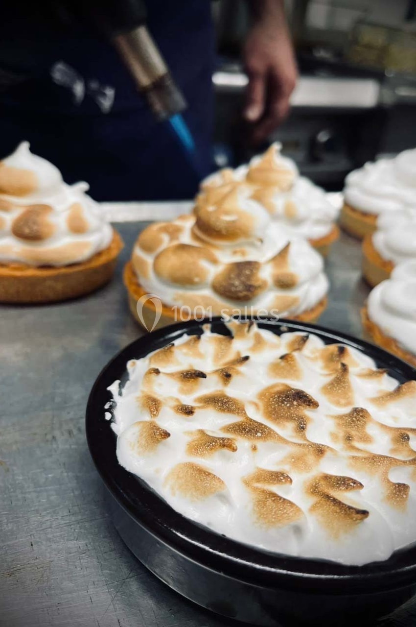Tartes meringuées dorées au chalumeau sur un plan de travail en cuisine.